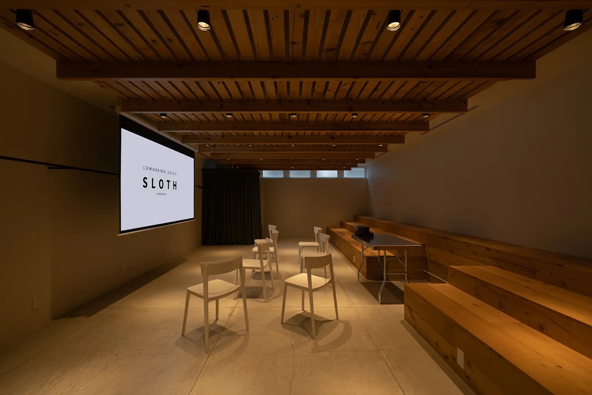 SLOTH JINNAN（スロース神南）SLOTHロゴを投影したイベントスペースと木製ステップ席
